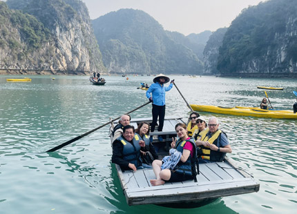 The excursion team guides guests through the Dark & Bright Cave via bamboo boat.